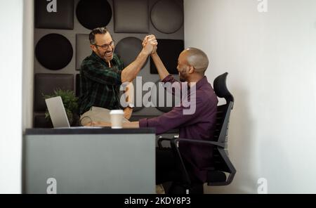 Two diverse business men and entrepreneurs high five and shake hands on successful meeting. Start up business teamwork and collaboration Stock Photo