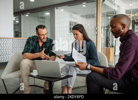 Casual meeting of smiling diverse business team analyzing financial data. Group team discussion in office lobby Stock Photo