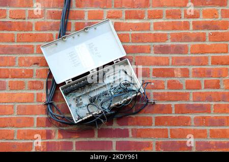 An outdoor telephone box with tangled wires and corrosion, haphazardly ...