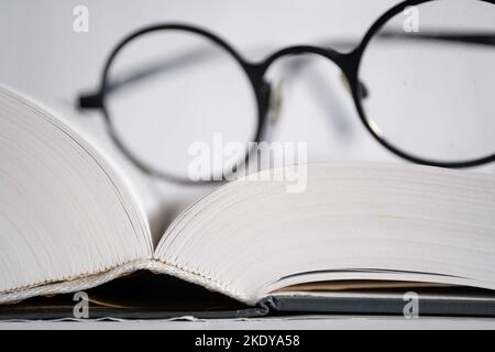 Glasses lie on the pages of an opened book, with shallow depth of field Stock Photo