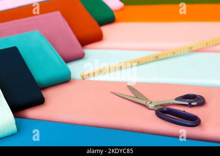 The blue scissors and meter rod on jersey cotton colored fabrics - the concept of sewing clothes Stock Photo