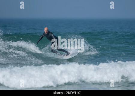 A mature male surfer riding a wave at Fistral in Newquay in Cornwall in the UK. Stock Photo
