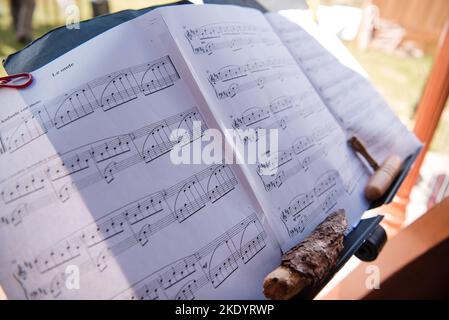 A closeup of music note sheets on a stand outdoors for a wedding event Stock Photo