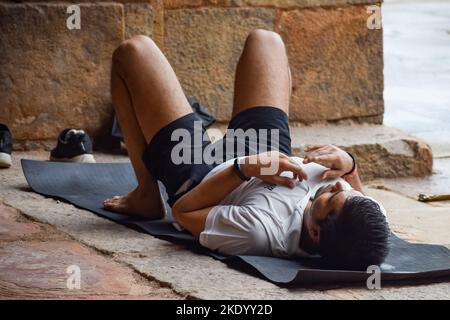 Delhi, India, June 18 2022 - Inspired Indian young man doing yoga asanas in Lodhi Garden Park, New Delhi, India. Young citizen exercising outside and Stock Photo