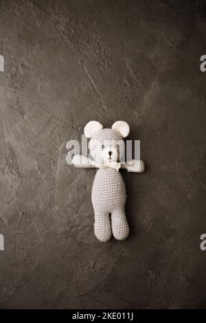 Crocheted bear in amigurumi style on a gray background Stock Photo