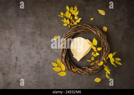 knitted yellow hat in a wreath of branches with yellow leaves Stock Photo