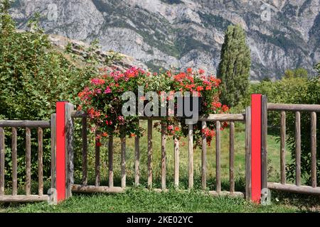 Wooden Boundary Fence with Red Supports and Planters with Red Geraniums Saint-Vincent-les-Forts Alpes-de-Haute-Provence France Stock Photo