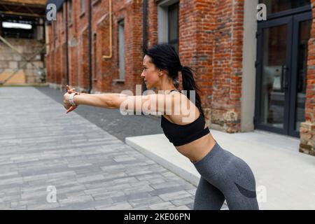 30s woman stretches her arms while exercising outdoors Stock Photo