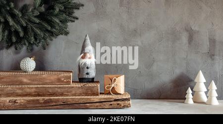 Cozy Christmas decorations on a gray background. Wreath, bauble, elf, gift box and white Christmas trees Stock Photo