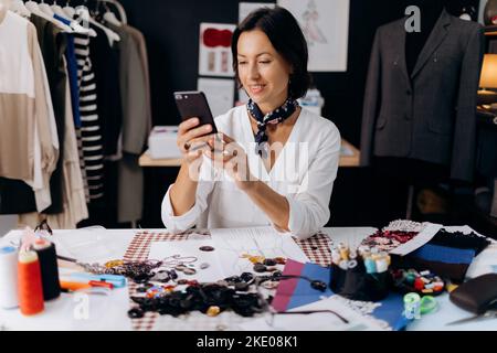 Seamstress using smartphone at work Stock Photo
