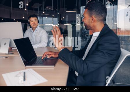 African business worker waving hi to his colleague while sitting together in modern coworking Stock Photo