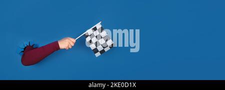 hand holding checkered flag over blue background, panoramic layout Stock Photo