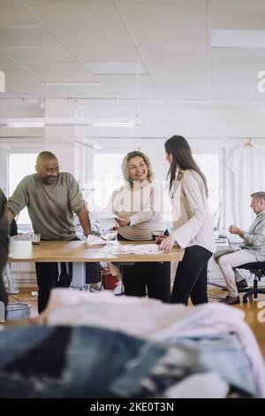 Smiling male and female fashion designers communicating with each other at workshop Stock Photo