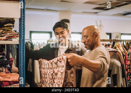 Male fashion designers examining fabric while standing at workshop Stock Photo