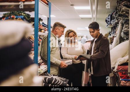 Multiracial fashion designers discussing while holding fabric at workshop Stock Photo