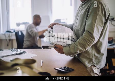 Midsection of male design professional holding packages at workshop Stock Photo