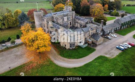 An aerial view of Walworth Castle with colorful autumn trees and parked vehicles in England Stock Photo