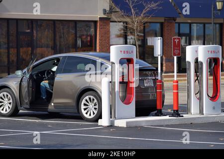 South Barrington, Illinois USA. Driver sits in vehicle while it is being recharged at a Tesla electric vehicle charging station at a shopping mall. Stock Photo