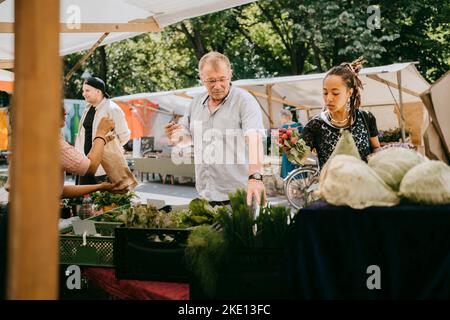 Customers buying organic vegetables from market Stock Photo
