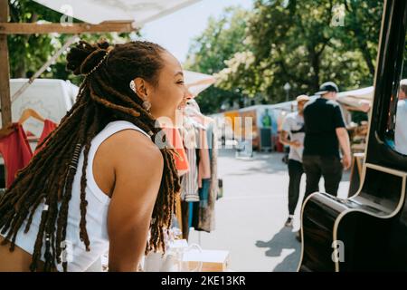 Side view of female owner with dreadlocks in stall at flea market Stock Photo