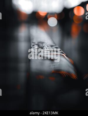 A railing covered in rain drops with a bokeh background in front of the famous Chicago theatre on a dark and rainy night Stock Photo