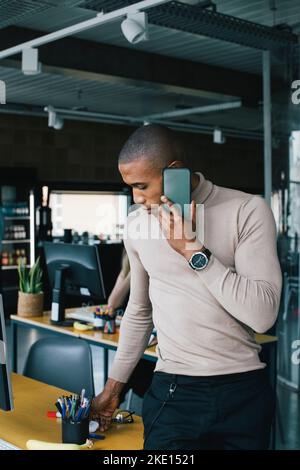 Young male computer programmer talking on smart phone in startup company Stock Photo