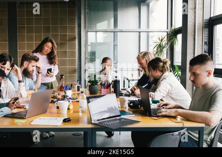 Multiracial business colleagues working on laptops at desk in startup company Stock Photo