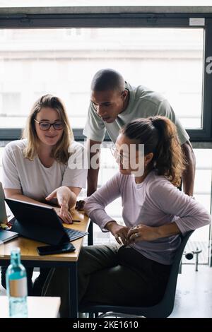 Multiracial female and male computer programmers discussing over laptop in office Stock Photo