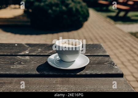 Brown Cup of coffe on wooden table in garden. Coffee Cup and saucer on napkin. Star anise and coffee Stock Photo