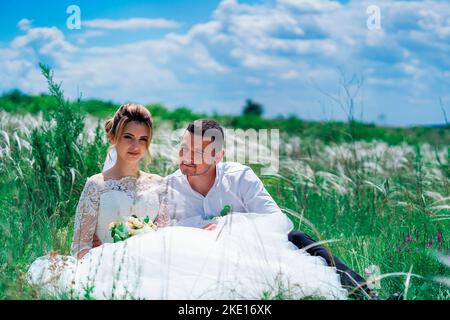 The bride and groom are sitting in a field Stock Photo