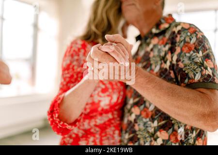 Senior couple holding hands while dancing together in class Stock Photo