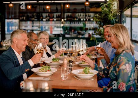 Happy senior male and female friends toasting wineglasses in restaurant Stock Photo