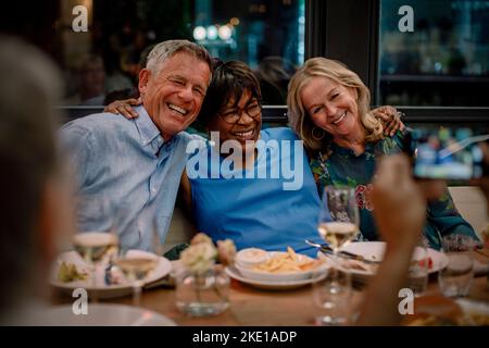Happy male and female senior friends enjoying in restaurant during night Stock Photo