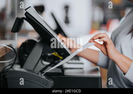 Saleswoman printing invoice or receipt for a customer in the shopping center, POS system, finance concept Stock Photo