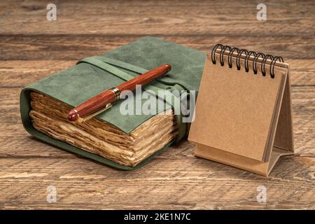 retro leather-bound journal with decked edge handmade paper pages and a blank calendar on a rustic wooden table, journaling concept Stock Photo