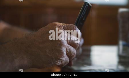 Senior male checking on his phone during the night. Bright touchscreen in the dark. Browsing social networks. Selective focus of a man using his phone Stock Photo