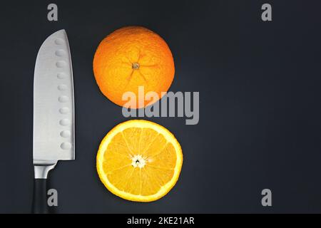 Close up harp stainless steel knife and fresh orange on dark background Stock Photo