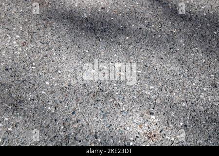 A light wall of stone chips with a shadow falling on it. The texture of the stone. Universal natural background. Stock Photo