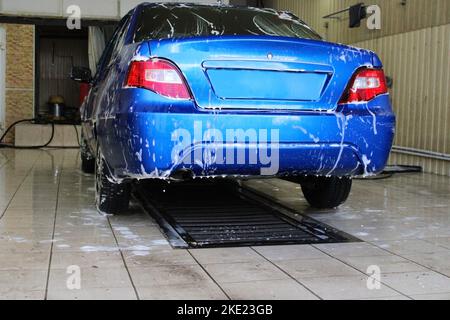 Blue car close-up at the car wash. Conception of ecology and environmental pollution. Stock Photo
