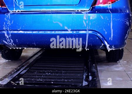 The back of a blue car close-up at a car wash. The concept of ecology and environmental pollution. Stock Photo