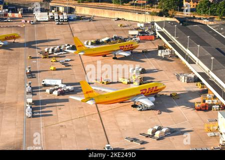 London, England - August 2022: Aerial view of cargo planes operated by DHL parked for unloading at the cargo terminal of an airport. Stock Photo