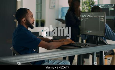African american coder developing app interface with html code and script on terminal window, programming it language. System egineer using database information in development agency. Stock Photo