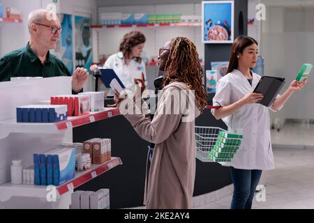 African american client talking with senior man in drugstore discussing about cardiology medication prescription. Customers purchasing pills, supplements, vitamine. Health care support Stock Photo