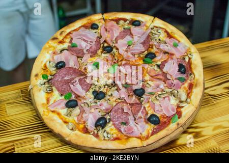 cooking pizza in the oven . Pizza near the stone stove with fire. Background of a traditional pizzeria restaurant with a fire place. Stock Photo