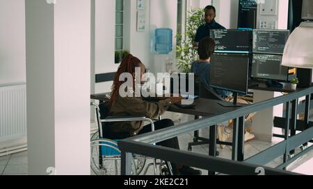 African american app developer in wheelchair analyzing software program, coding html script with it web language. System programmer with impairment coding new server interface. Stock Photo