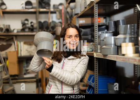 Woman choosing plastic pipe fittings in shop of building materials Stock Photo