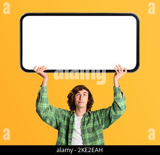 Teen Hipster Guy Holding Big Blank Smartphone With White Screen Above Head Stock Photo