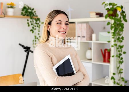 Happy young business woman holding digital tablet standing in office studio Stock Photo