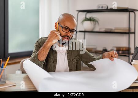 Concentrated busy mature latin man engineer in glasses thinking about project in home office interior Stock Photo