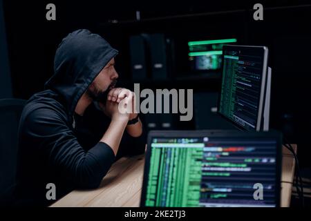Hacker with computers indoors Stock Photo